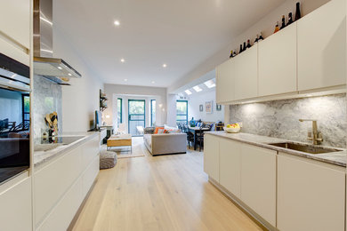 This is an example of a medium sized contemporary galley kitchen/diner in London with a built-in sink, flat-panel cabinets, white cabinets, marble worktops, grey splashback, marble splashback, integrated appliances, light hardwood flooring, no island and grey floors.