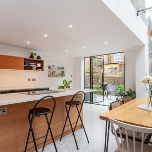 Ispirazione per una grande cucina design con lavello a vasca singola, ante lisce, ante verdi, top in superficie solida, paraspruzzi bianco, elettrodomestici neri, pavimento alla veneziana, pavimento grigio e top bianco