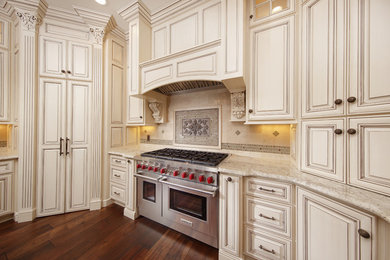 Enclosed kitchen - mid-sized transitional u-shaped dark wood floor and brown floor enclosed kitchen idea in Other with raised-panel cabinets, white cabinets, granite countertops, beige backsplash, travertine backsplash, stainless steel appliances and an undermount sink