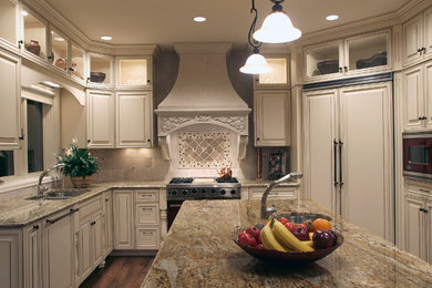 Inspiration for a mid-sized timeless u-shaped dark wood floor and brown floor kitchen remodel in Denver with a double-bowl sink, raised-panel cabinets, beige cabinets, granite countertops, beige backsplash, ceramic backsplash, paneled appliances and an island