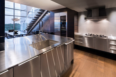 Example of a trendy kitchen design in Montreal with an integrated sink, stainless steel cabinets and stainless steel countertops