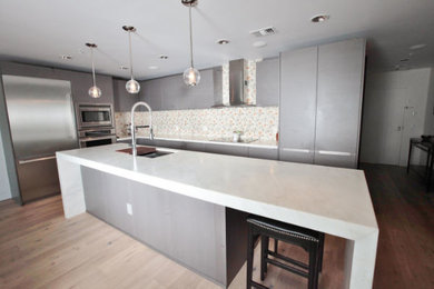 Inspiration for a large contemporary l-shaped medium tone wood floor eat-in kitchen remodel in Tampa with an undermount sink, flat-panel cabinets, gray cabinets, quartz countertops, multicolored backsplash, ceramic backsplash, stainless steel appliances and an island