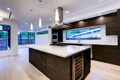 This is an example of a modern galley kitchen/diner in Houston with a submerged sink, brown cabinets, engineered stone countertops, white splashback and an island.