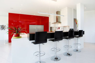 モントリオールにあるラグジュアリーな広いコンテンポラリースタイルのおしゃれなキッチン (フラットパネル扉のキャビネット、赤いキャビネット、クオーツストーンカウンター、白いキッチンパネル、ガラス板のキッチンパネル、シルバーの調理設備) の写真