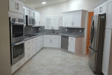 Example of a mid-sized minimalist u-shaped beige floor eat-in kitchen design in Miami with a double-bowl sink, shaker cabinets, white cabinets, gray backsplash, stainless steel appliances and no island