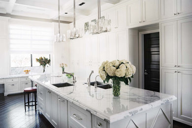 Example of a huge trendy u-shaped dark wood floor eat-in kitchen design in Miami with a drop-in sink, raised-panel cabinets, white cabinets, marble countertops, white backsplash, stone slab backsplash, paneled appliances and two islands