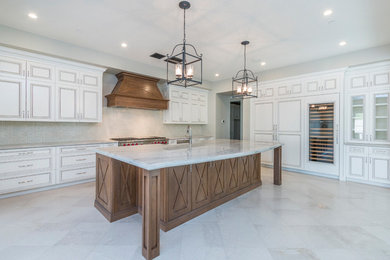 Example of a huge transitional l-shaped limestone floor and beige floor open concept kitchen design in Phoenix with a farmhouse sink, raised-panel cabinets, white cabinets, quartzite countertops, white backsplash, stone tile backsplash, paneled appliances and an island
