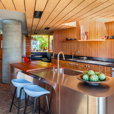 Inspiration for a 1950s brown floor eat-in kitchen remodel in Los Angeles with an integrated sink, medium tone wood cabinets, stainless steel countertops, brown backsplash, wood backsplash, paneled appliances and an island