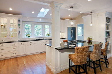 Example of a large classic single-wall light wood floor and beige floor open concept kitchen design in Boston with granite countertops, an island, an undermount sink, shaker cabinets, white cabinets, white backsplash, subway tile backsplash, stainless steel appliances and black countertops