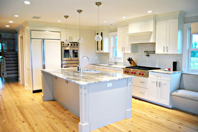 Inspiration for a large contemporary galley eat-in kitchen remodel in New York with an undermount sink, shaker cabinets, white cabinets, white backsplash, subway tile backsplash, stainless steel appliances and an island