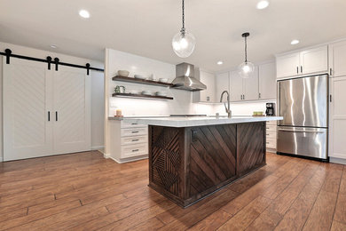 Eat-in kitchen - mid-sized transitional l-shaped laminate floor eat-in kitchen idea in San Francisco with an undermount sink, shaker cabinets, white cabinets, solid surface countertops, white backsplash, ceramic backsplash, stainless steel appliances, an island and gray countertops