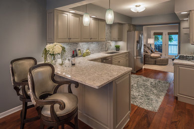 Eat-in kitchen - mid-sized traditional l-shaped medium tone wood floor and brown floor eat-in kitchen idea in Other with an undermount sink, raised-panel cabinets, gray cabinets, granite countertops, gray backsplash, stone tile backsplash, stainless steel appliances and a peninsula