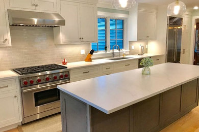 Large transitional galley light wood floor and brown floor eat-in kitchen photo in New York with an undermount sink, shaker cabinets, white cabinets, quartz countertops, gray backsplash, porcelain backsplash, stainless steel appliances, an island and white countertops