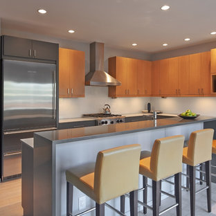 Design ideas for a mid-sized contemporary l-shaped open plan kitchen in Seattle with with island, flat-panel cabinets, light wood cabinets, quartz benchtops, blue splashback, glass sheet splashback, stainless steel appliances, an undermount sink and bamboo floors.