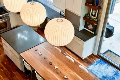 Foto på ett funkis grå u-kök, med en rustik diskho, släta luckor, vita skåp, grått stänkskydd, stänkskydd i porslinskakel, rostfria vitvaror, mellanmörkt trägolv, en köksö och flerfärgat golv