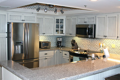 Eat-in kitchen - mid-sized traditional l-shaped eat-in kitchen idea in Orlando with an undermount sink, recessed-panel cabinets, white cabinets, granite countertops, multicolored backsplash, mosaic tile backsplash, stainless steel appliances and a peninsula