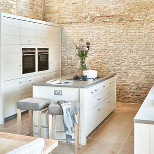 Foto di una cucina abitabile country con lavello a vasca singola, ante grigie, isola, pavimento beige e top grigio
