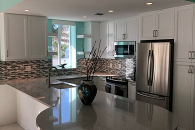 Example of a small transitional l-shaped eat-in kitchen design in Miami with white cabinets and an island