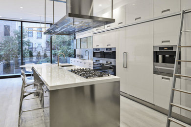 Foto di una cucina moderna di medie dimensioni con ante bianche, lavello sottopiano, ante lisce, top in superficie solida, elettrodomestici in acciaio inossidabile, parquet chiaro e pavimento beige
