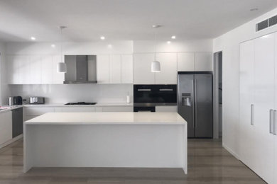 Design ideas for a large modern l-shaped kitchen pantry in Brisbane with a submerged sink, flat-panel cabinets, white cabinets, engineered stone countertops, white splashback, glass sheet splashback, stainless steel appliances, an island, marble flooring and green floors.