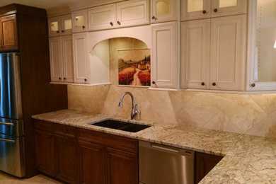 Example of a mid-sized tuscan kitchen design in Other with an undermount sink, raised-panel cabinets, light wood cabinets, granite countertops, beige backsplash, stone tile backsplash and stainless steel appliances