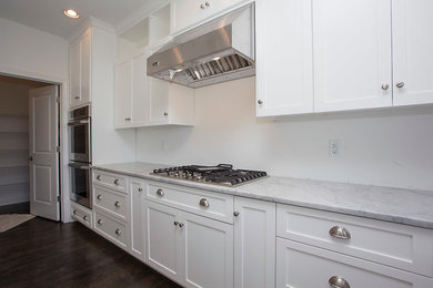 Foto de cocinas en L contemporánea grande con armarios estilo shaker, puertas de armario blancas, encimera de mármol, electrodomésticos de acero inoxidable, suelo de madera oscura y suelo marrón
