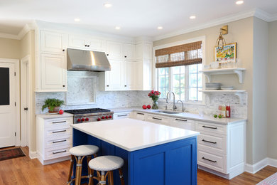 Inspiration for a timeless l-shaped medium tone wood floor kitchen remodel in New York with an undermount sink, white cabinets, quartz countertops, white backsplash, marble backsplash, stainless steel appliances, an island and raised-panel cabinets