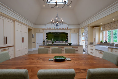 Exempel på ett mycket stort klassiskt grå grått kök och matrum, med en rustik diskho, skåp i shakerstil, gula skåp, granitbänkskiva, grönt stänkskydd, glaspanel som stänkskydd, integrerade vitvaror, klinkergolv i keramik, en köksö och flerfärgat golv