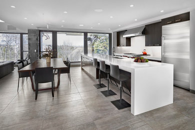 Inspiration for a large contemporary galley gray floor and porcelain tile open concept kitchen remodel in Edmonton with a double-bowl sink, flat-panel cabinets, dark wood cabinets, white backsplash, stainless steel appliances, an island, solid surface countertops and glass sheet backsplash