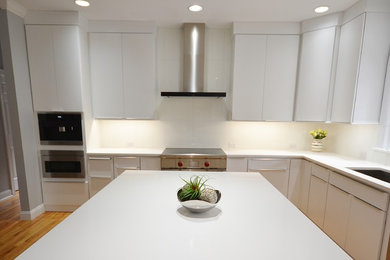 Design ideas for a large scandinavian l-shaped kitchen/diner in Philadelphia with a submerged sink, flat-panel cabinets, white cabinets, engineered stone countertops, white splashback, ceramic splashback, stainless steel appliances, medium hardwood flooring, an island and brown floors.