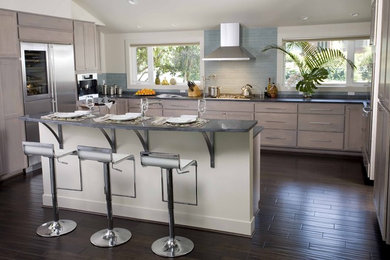 Example of a large trendy u-shaped dark wood floor and brown floor open concept kitchen design in Seattle with an undermount sink, shaker cabinets, light wood cabinets, blue backsplash, glass tile backsplash, stainless steel appliances and an island