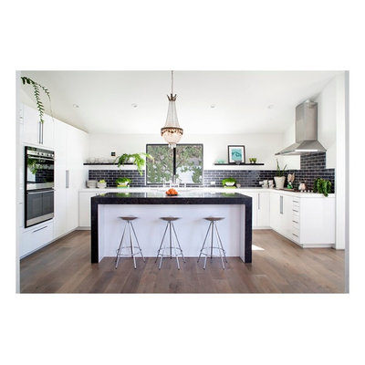 Eat-in kitchen - mid-sized modern u-shaped dark wood floor and brown floor eat-in kitchen idea in Orange County with an undermount sink, flat-panel cabinets, white cabinets, solid surface countertops, black backsplash, subway tile backsplash, stainless steel appliances and an island