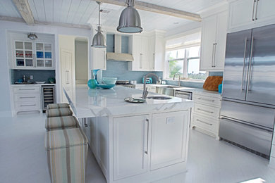 Imagen de cocina minimalista abierta con puertas de armario blancas, encimera de mármol, salpicadero azul, electrodomésticos de acero inoxidable y una isla
