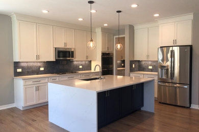 Eat-in kitchen - contemporary light wood floor and gray floor eat-in kitchen idea in Denver with an undermount sink, flat-panel cabinets, white cabinets, quartz countertops, blue backsplash, ceramic backsplash, stainless steel appliances, an island and white countertops