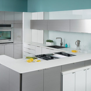 Kitchen - contemporary u-shaped kitchen idea in Chicago with a drop-in sink, flat-panel cabinets, white cabinets, white backsplash, glass sheet backsplash, stainless steel appliances and a peninsula