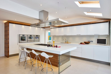 Inspiration for a large contemporary l-shaped kitchen/diner in Cambridgeshire with a submerged sink, flat-panel cabinets, white cabinets, composite countertops, grey splashback, glass sheet splashback, stainless steel appliances, limestone flooring and an island.