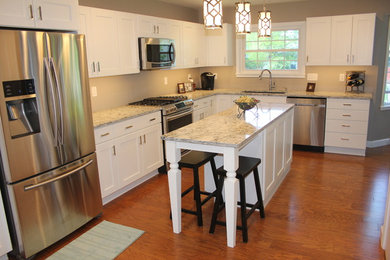 Inspiration for a large transitional l-shaped medium tone wood floor and brown floor open concept kitchen remodel in St Louis with an undermount sink, shaker cabinets, white cabinets, granite countertops, beige backsplash, stainless steel appliances and an island