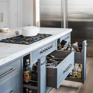 Idee per un cucina con isola centrale chic con ante blu, elettrodomestici in acciaio inossidabile e parquet chiaro