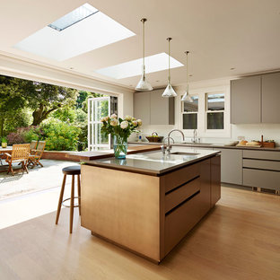 Inspiration for a large contemporary u-shaped kitchen in London with grey cabinets, quartz worktops, beige splashback, glass sheet splashback, stainless steel appliances, light hardwood flooring, an island, beige floors, grey worktops and flat-panel cabinets.