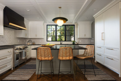 Eat-in kitchen - mid-sized modern u-shaped medium tone wood floor and brown floor eat-in kitchen idea in St Louis with an undermount sink, flat-panel cabinets, white cabinets, soapstone countertops, white backsplash, marble backsplash, paneled appliances, an island and black countertops