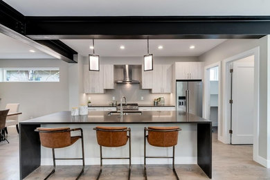 Photo of a contemporary galley kitchen in Denver with flat-panel cabinets, white cabinets, engineered stone countertops, stainless steel appliances, an island and grey worktops.