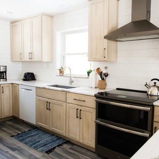 This is an example of a mid-sized transitional u-shaped separate kitchen in Other with an undermount sink, flat-panel cabinets, beige cabinets, quartz benchtops, white splashback, subway tile splashback, black appliances, vinyl floors, a peninsula, brown floor and white benchtop.