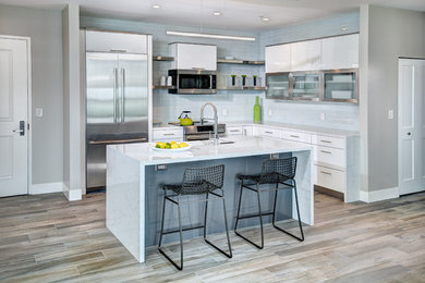 Inspiration for a small contemporary l-shaped kitchen/diner in Sacramento with a submerged sink, flat-panel cabinets, white cabinets, engineered stone countertops, white splashback, metro tiled splashback, stainless steel appliances, porcelain flooring, an island, grey floors and white worktops.