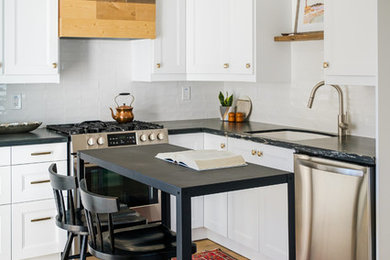 Inspiration for a small modern l-shaped vinyl floor and beige floor eat-in kitchen remodel in San Diego with an undermount sink, shaker cabinets, white cabinets, quartzite countertops, white backsplash, ceramic backsplash, stainless steel appliances, an island and black countertops