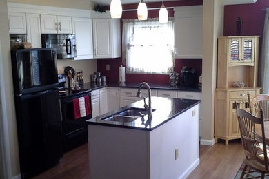 Example of a small classic l-shaped dark wood floor and brown floor eat-in kitchen design in New York with a double-bowl sink, raised-panel cabinets, white cabinets, quartz countertops, black appliances and an island