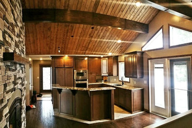 Design ideas for a medium sized rustic l-shaped kitchen/diner in Other with a submerged sink, shaker cabinets, brown cabinets, granite worktops, stainless steel appliances, dark hardwood flooring, an island and brown floors.