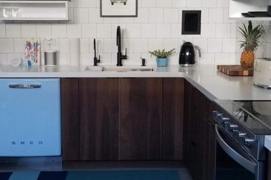 Small minimalist u-shaped eat-in kitchen photo in Hawaii with an undermount sink, flat-panel cabinets, dark wood cabinets, solid surface countertops, white backsplash, ceramic backsplash, colored appliances and white countertops
