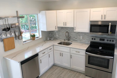 Example of a small arts and crafts l-shaped ceramic tile and gray floor eat-in kitchen design in Tampa with an undermount sink, shaker cabinets, white cabinets, quartz countertops, multicolored backsplash, glass tile backsplash, stainless steel appliances, no island and white countertops