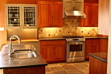 Example of an arts and crafts slate floor and green floor kitchen design in Philadelphia with an undermount sink, shaker cabinets, medium tone wood cabinets, soapstone countertops, green backsplash, slate backsplash and stainless steel appliances