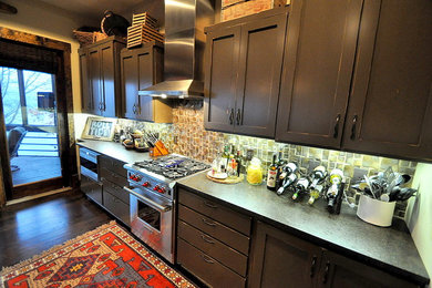 Mid-sized elegant single-wall dark wood floor enclosed kitchen photo in Birmingham with an undermount sink, flat-panel cabinets, brown cabinets, granite countertops, multicolored backsplash, ceramic backsplash, stainless steel appliances and no island